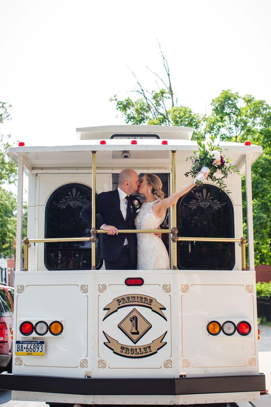 bride and groom kiss on trolley with bouquet