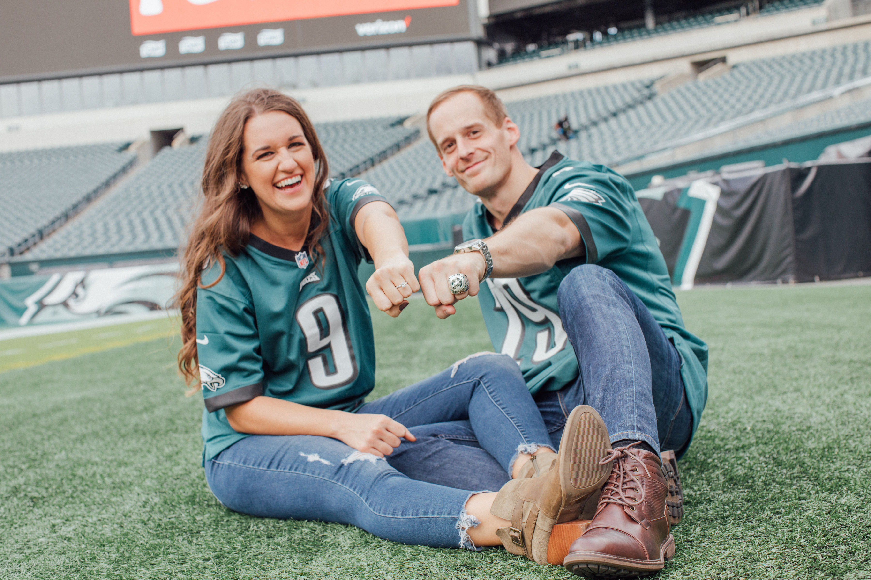 couple sitting wearing jerseys in football field