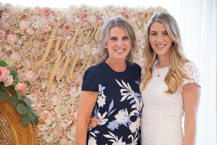 bride and mom pose in front of floral wall