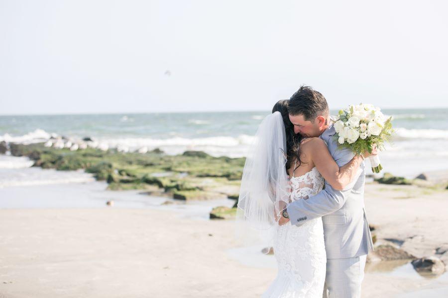 bride and groom embrace on beach