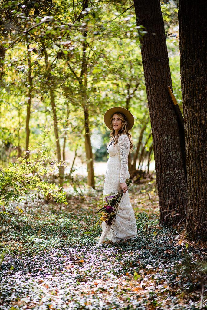 bride wearing hat and crochet wedding dress in woods