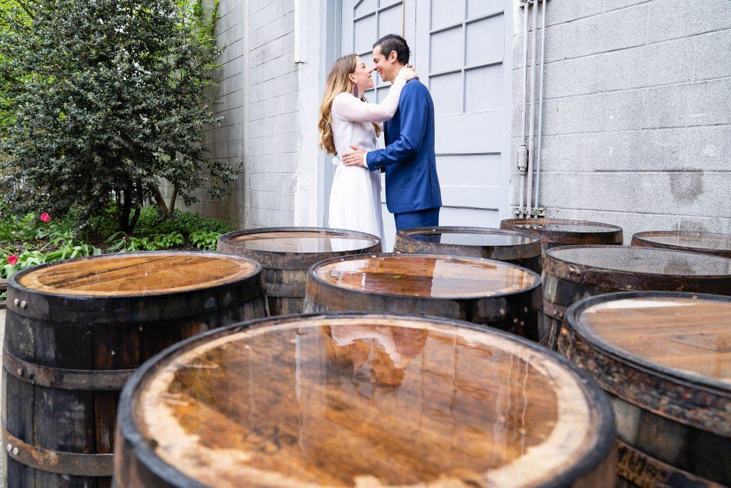bride and groom hug in front of beer barrels