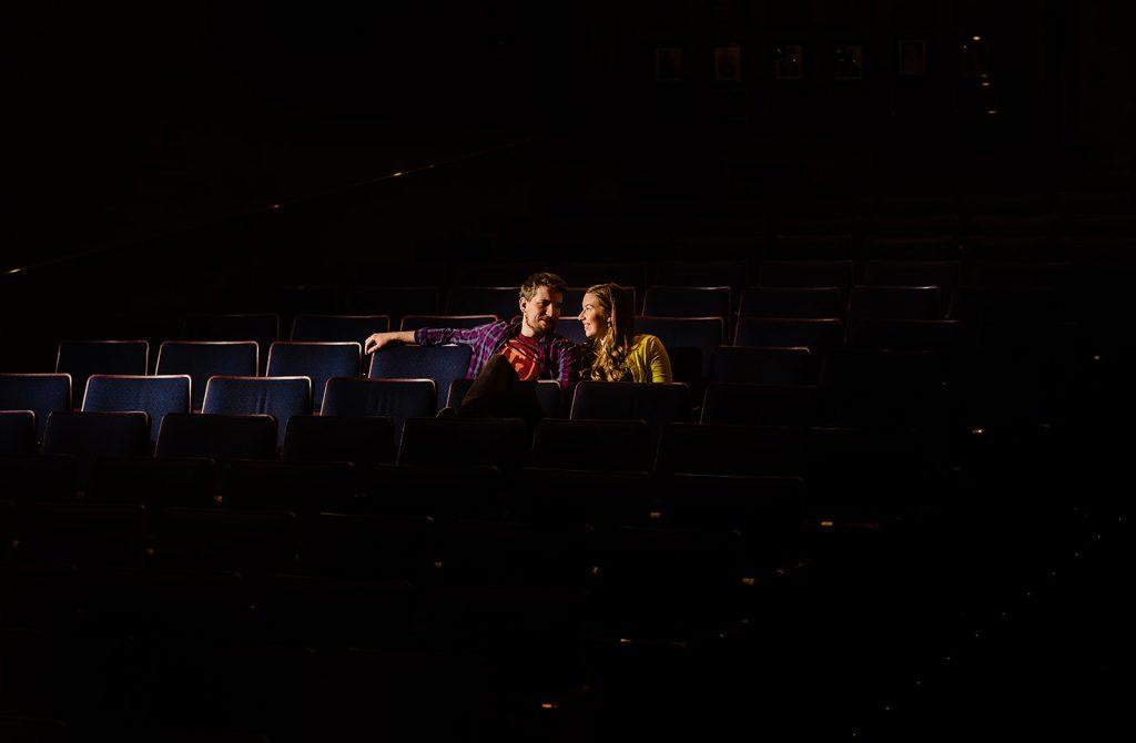 engaged couple sit in darkened theatre